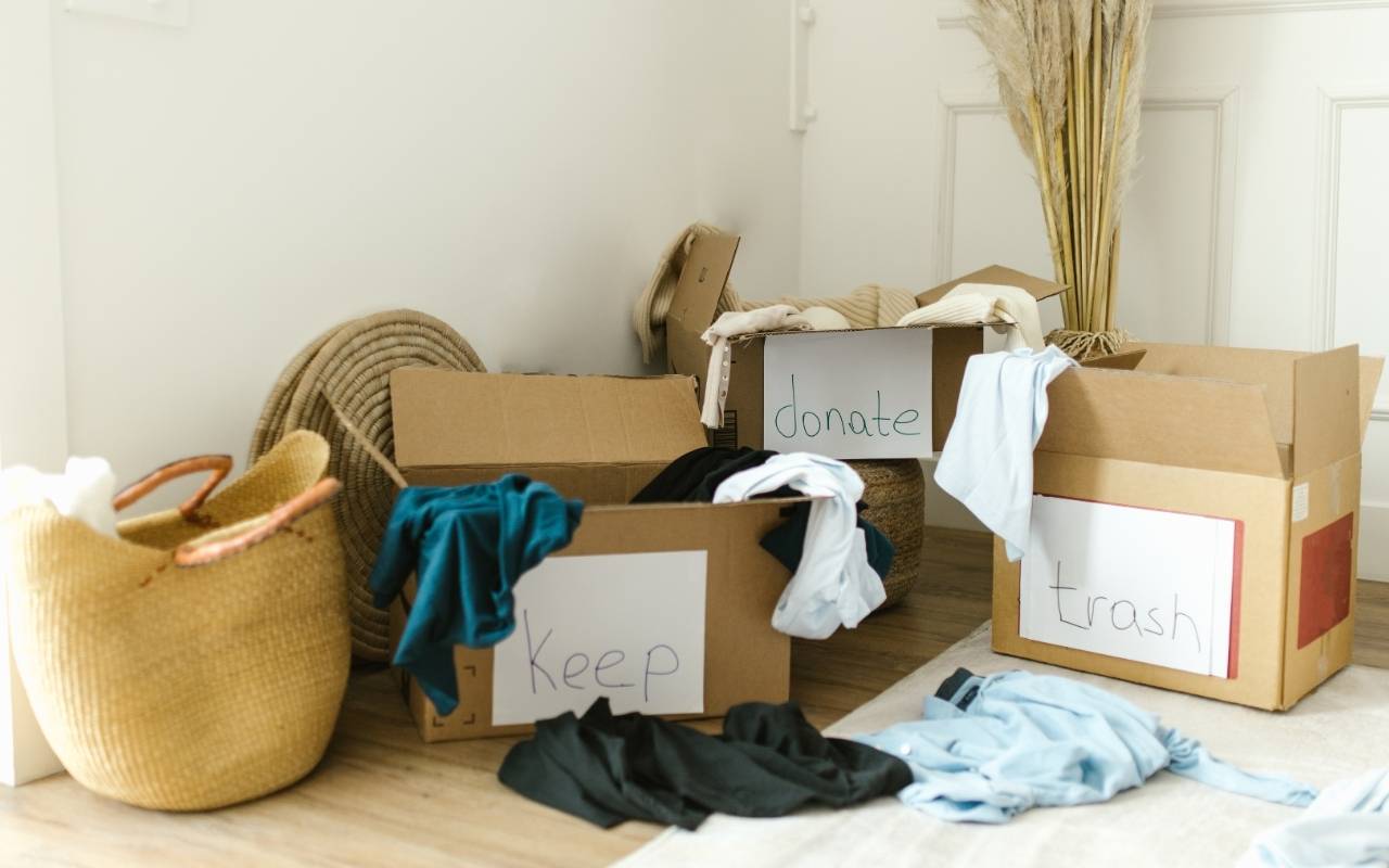 Person sorting boxes and clothes in a small San Francisco apartment