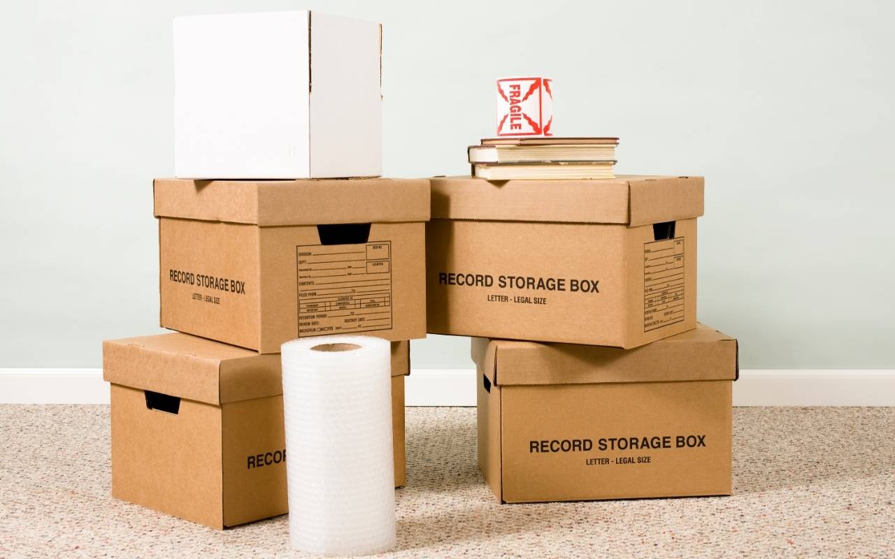 Close-up of moving boxes labeled by room for organized downsizing